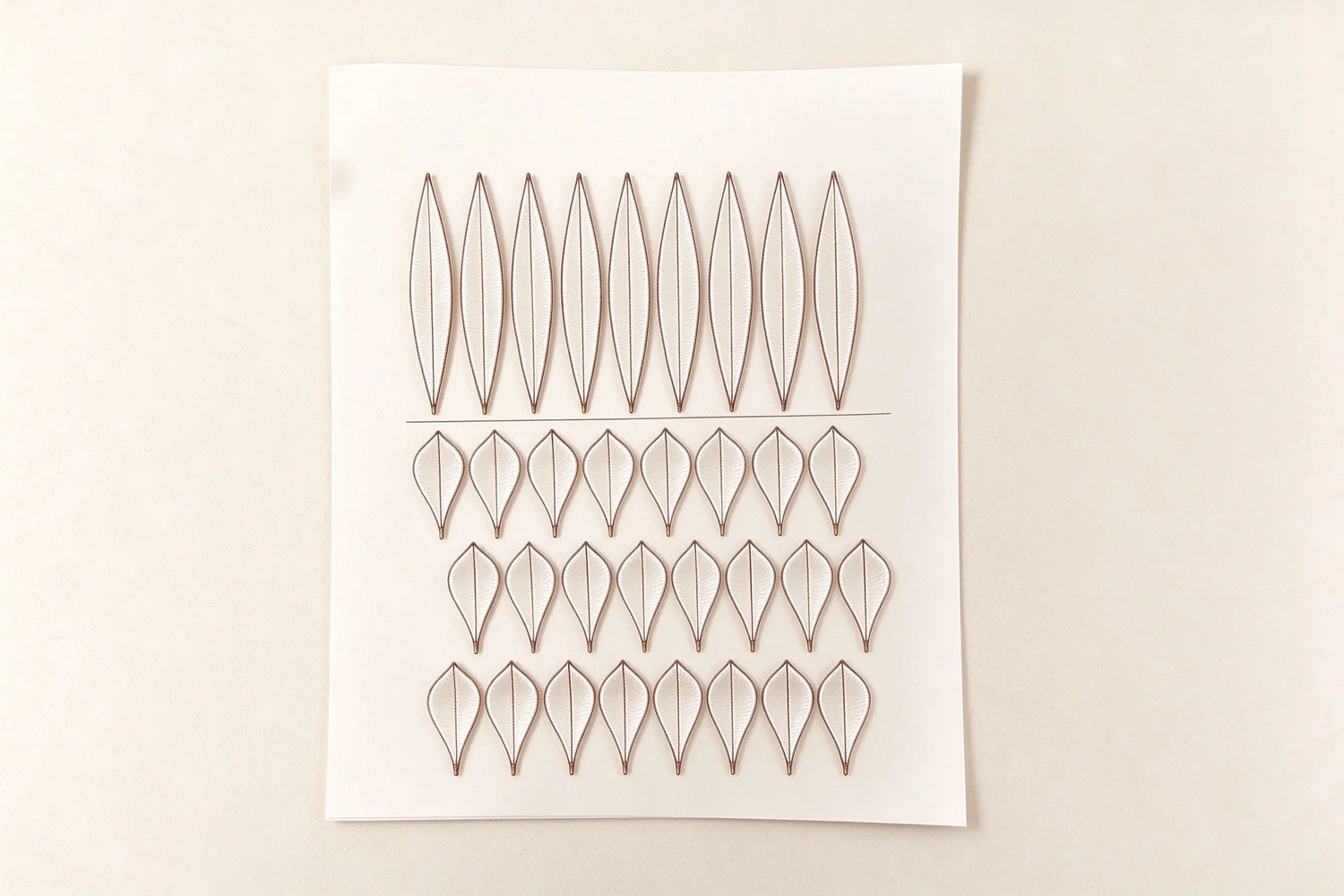 Shaped copper wire petal frames lined up on the workbench before any silk is wrapped on